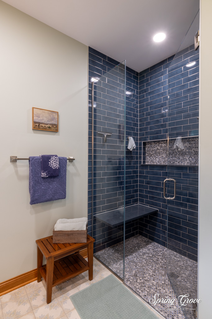 The walk-in shower is covered floor to ceiling with blue subway tile and features a bench alongside a coin tiled recess for any self-like needs.
